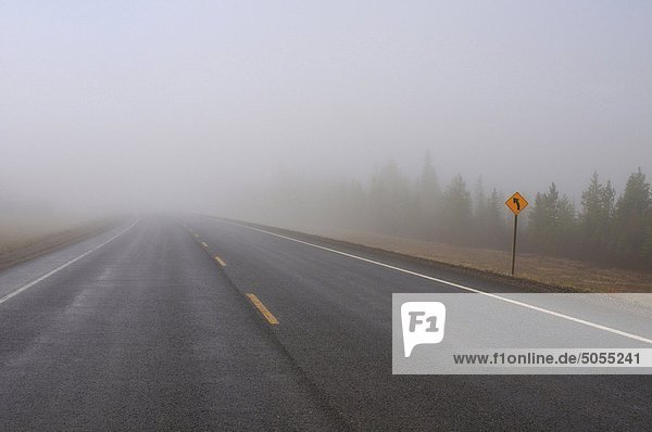 Eine zwei Lane Blacktop Autobahn Streches in die Dunst und Nebel auf einem feuchten Alberta-Morgen