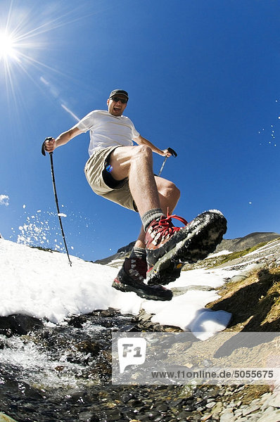A hiker leaps across an alpine stream above Garibaldi Lake in Garibaldi Provincial Park  BC.