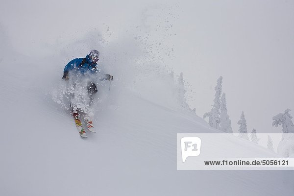 Eine männliche Skifahrer macht eine tiefe Wendung in Revelstoke Mtn Resort  BC