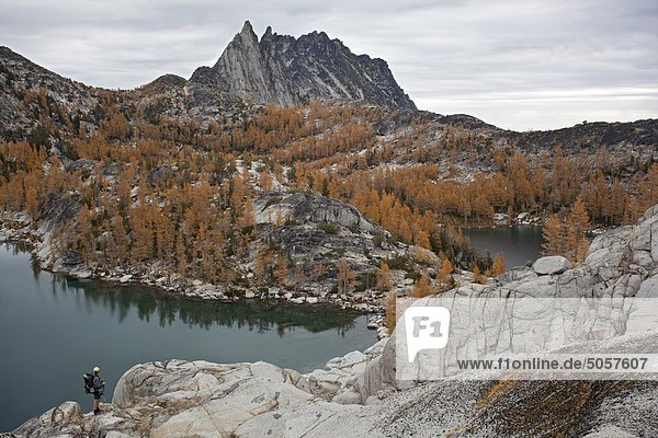 Hiker overlooking Inspiration and Perfection Lakes and Prusik Peak in the Upper Enchantments Basin  Alpine Lakes Wilderness  Washington State  United States of America