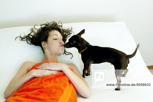 Frau liegend im Bett mit Hund