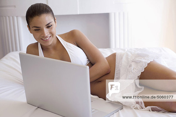 Woman lying on bed using laptop