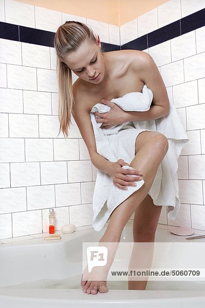 Woman standing in bathtub drying herself