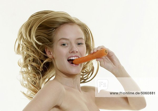 Naked woman eating carrot