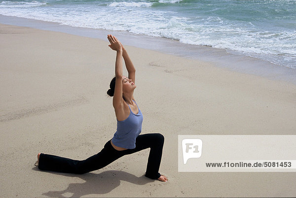 Woman practising yoga on the beach