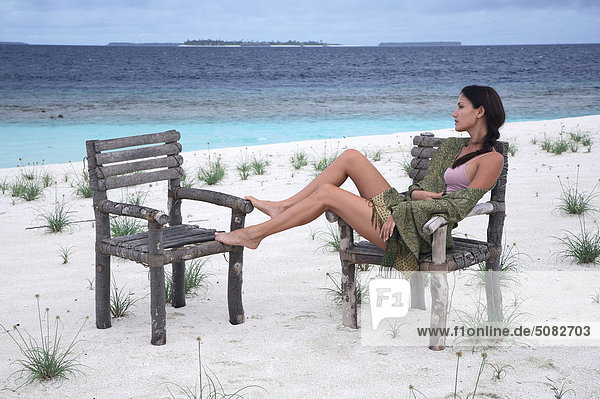 Frau sitzt auf Stuhl am Meer auf den Malediven