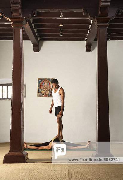 Mann assisting Frau macht yoga