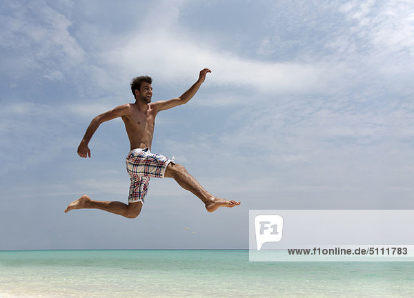 Mann beim Springen am tropischen Strand