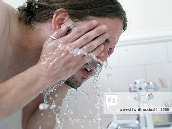 Mann wäscht sich das Gesicht im Bad