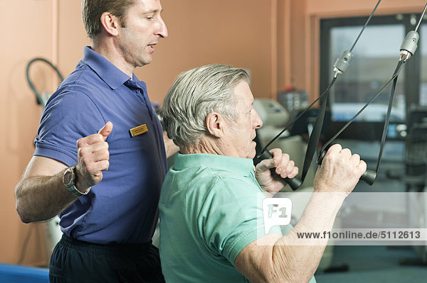 Trainer helping older man exercise