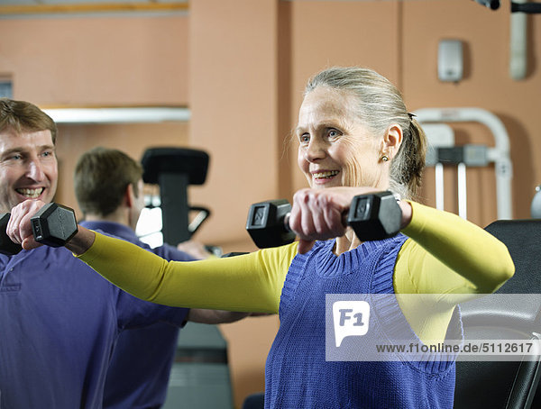 Ältere Frau beim Heben von Gewichten im Fitnessstudio