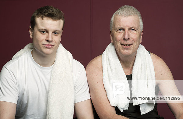 Vater und Sohn mit Handtüchern im Fitnessstudio