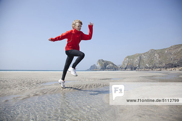 Boy jumping over pools on beach