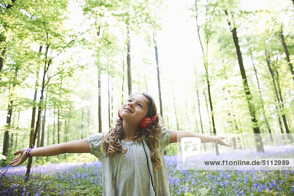 Girl listening to headphones in forest