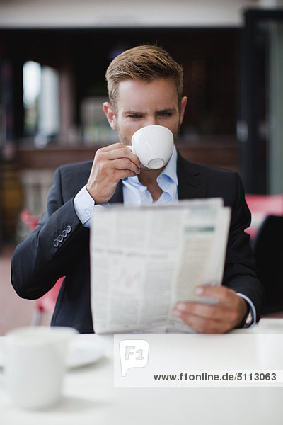 Businessman having coffee with newspaper
