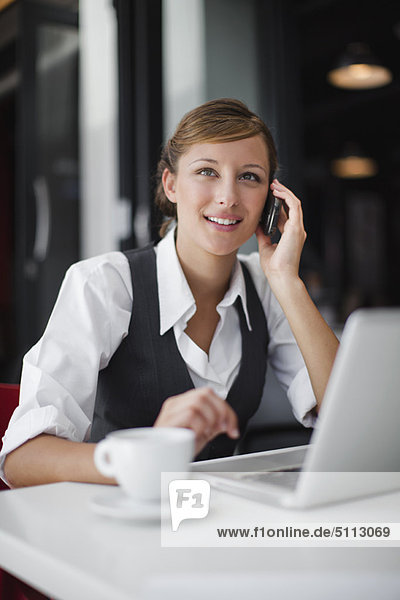 Businesswoman on cell phone with laptop