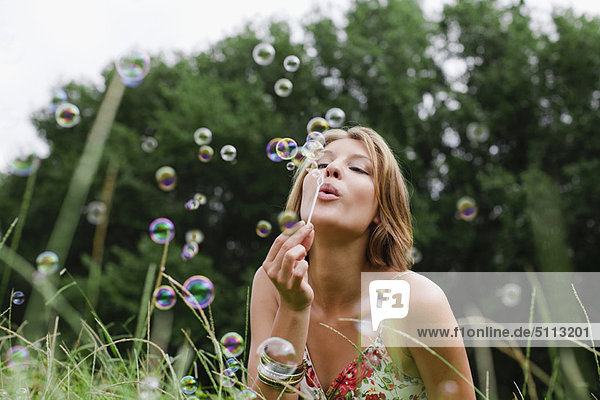Woman blowing bubbles in field