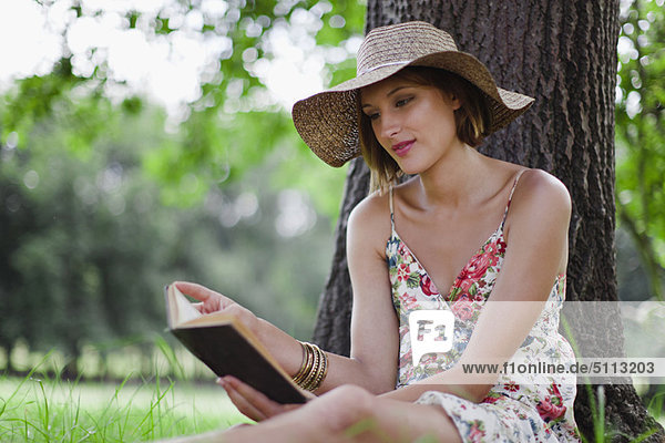 Woman reading against tree in field
