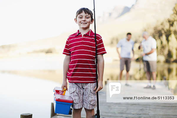 Boy carrying fishing rod on jetty