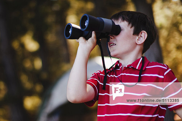 Boy using binoculars at campsite