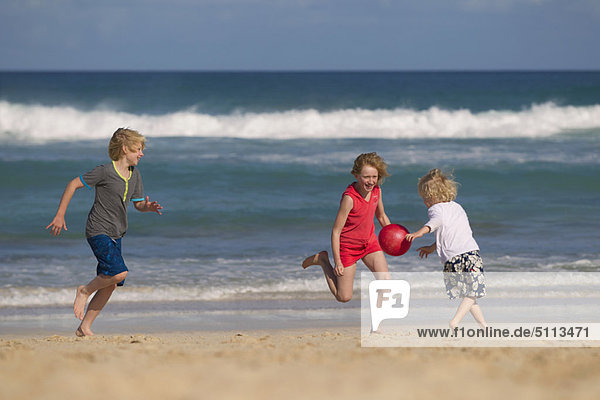 Children playing with red ball on beach