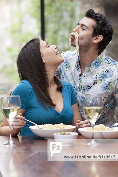 Playful couple eating together at table