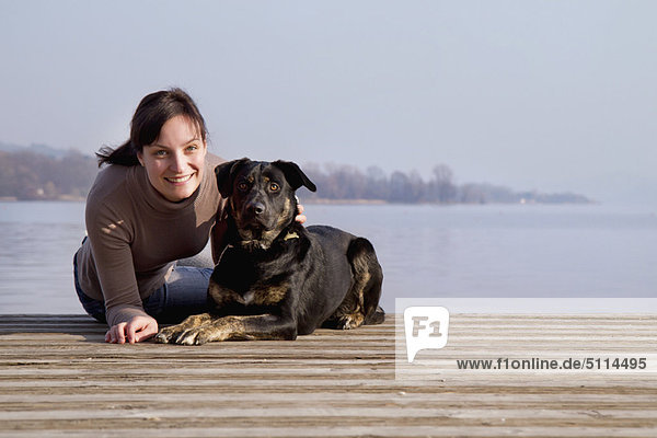 Woman sitting with dog on dock