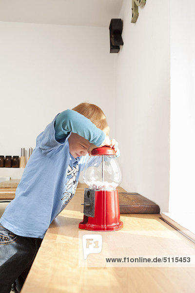 Junge öffnet Gummiballmaschine in der Küche