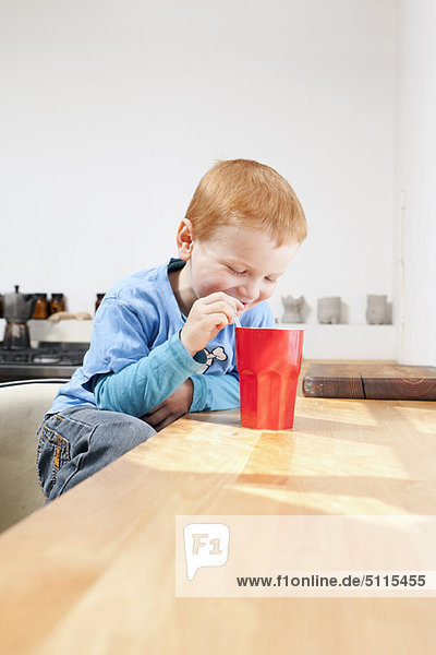 Junge trinkt aus Stroh in der Küche