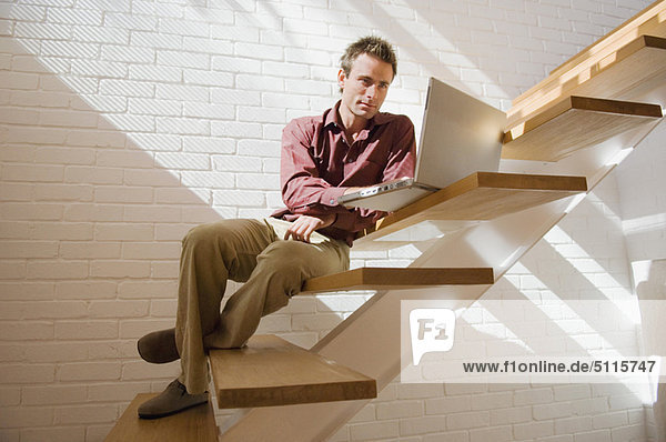 Man using laptop on steps