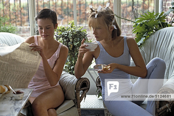 Young women sitting on a wicker chair in a veranda