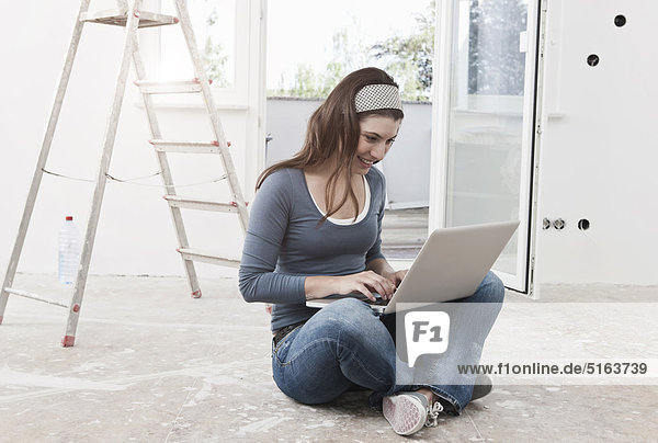 Young woman at renovating apartment working on laptop