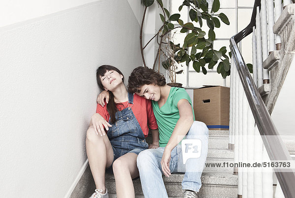 Deutschland  Köln  Junges Paar ruht auf einer Treppe in einer renovierten Wohnung