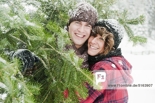 Österreich  Land Salzburg  Flachau  Junger Mann und Frau mit Weihnachtsbaum