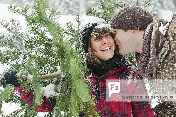 Österreich  Land Salzburg  Flachau  Junger Mann und Frau mit Weihnachtsbaum