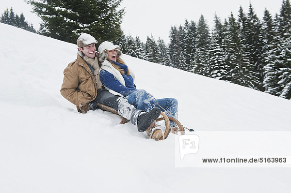 Austria  Salzburg Country  Flachau  Young man and woman tobogganging in snow