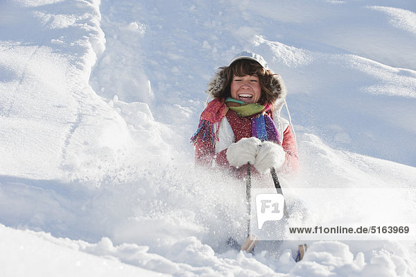 Österreich  Salzburger Land  Flachau  Junge Frau beim Schlittenfahren im Schnee