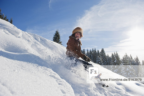 Österreich Salzburger Land Flachau Junge Frau beim Rodeln im Schnee