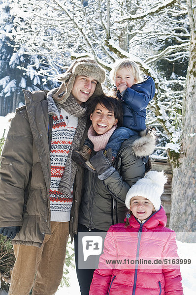 Austria  Salzburg Country  Flachau  View of family standing in snow  smiling  portrait