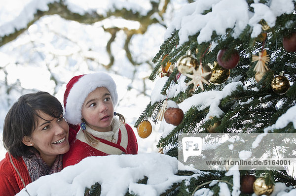 Österreich  Salzburger Land  Flachau  Junge Mutter und Tochter beim Blick auf den Weihnachtsbaum