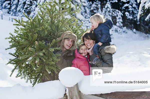 Österreich  Salzburger Land  Flachau  Ansicht der Familie mit Weihnachtsbaum im Schnee