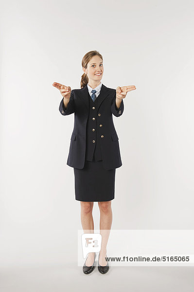 Young air stewardess with gun sign against white background  smiling  portrait