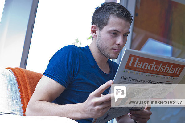Junger Mann liest Zeitung