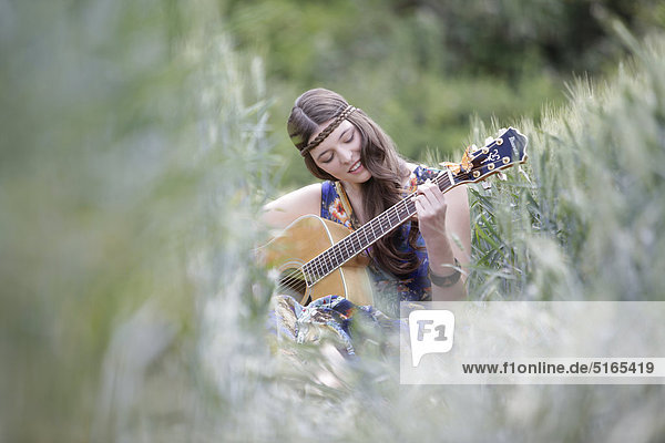 Junge Frau mit Gitarre im Kornfeld