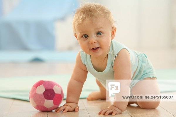 Baby mit einem Ball auf dem Fußboden