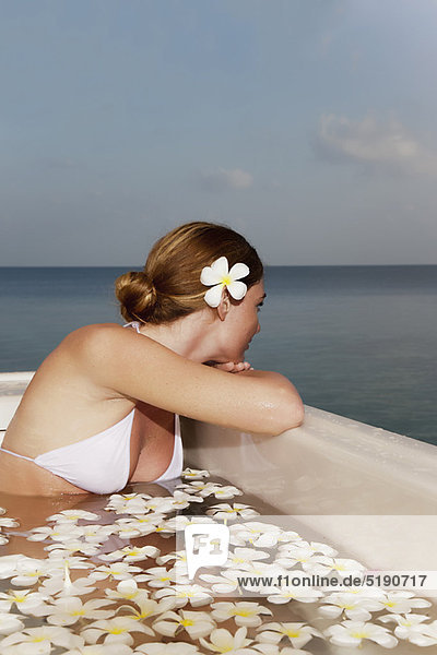 Woman sitting in pool with flowers