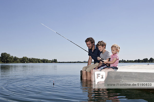 Father and children fishing on dock