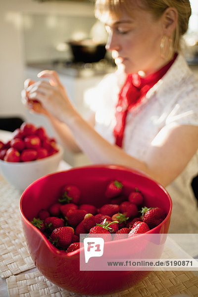Woman paring strawberries in kitchen