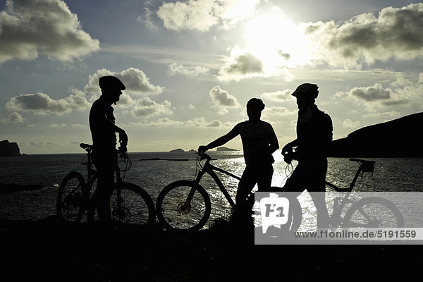 Silhouetten von Mountainbikern am See
