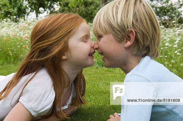 Children touching noses in field